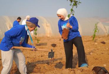 UN Volunteers Ola Al-Zubi (left) and Lina Kadri (right) planting a citrus tree in Deir 'Alla, Jordan Valley, in celebration of International Volunteer Day 2022.