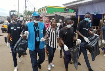 Refugee UN Volunteer Mbabazi Mugemana (in blue) participates in a clean-up campaign across Yaoundé's districts in June 2021. He is joined by footballer Ajara Nchout Njoya, youth from the DAFI programme, representatives from the refugee committees in Cameroonian communes and partners from Plan International.