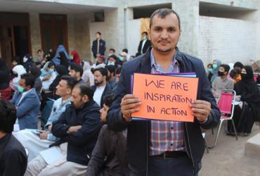 Ezat Ullah, Oficial de Inclusión Social y Empoderamiento de los Grupos Jóvenes Voluntario nacional de las Naciones Unidas del Programa de las Naciones Unidas para el Desarrollo (PNUD) en Pakistán, sostiene una pancarta en la celebración del Día Internacional de los Voluntarios en la comunidad de refugiados el 5 de diciembre de 2021.