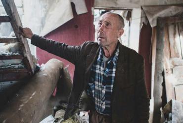 Un homme âgé montre la maison qu’il avait construite pour ses enfants et qui a été en grande partie détruite en raison des hostilités en cours dans le village de Zhovanka, oblast de Donetsk, Ukraine.