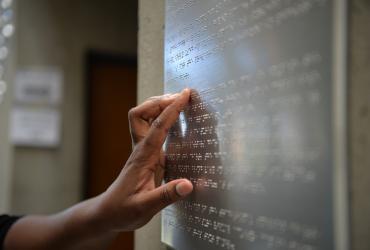 information panel in braille at an office setting being read by a hand