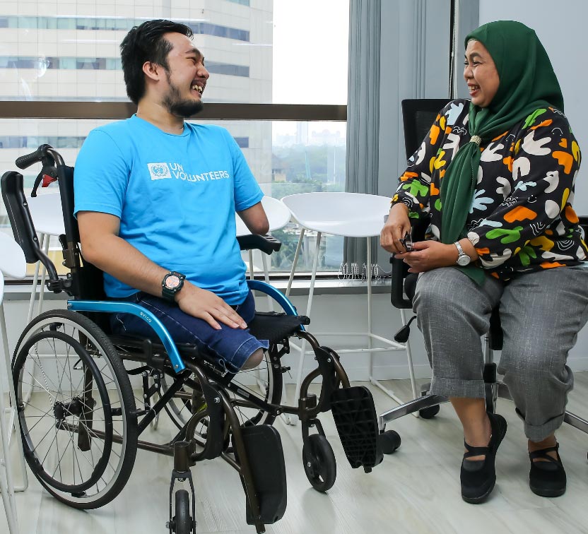 UN Volunteer in a wheel chair speaks with woman