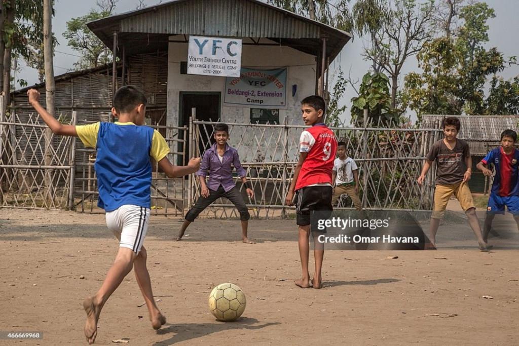 A group of young refugees play football on a field inside the Youth Friendly center funded by the UN High Commissioner for Refugees (UNHCR) in the Beldangi 2 refugee camp on March 14, 2015, in Beldangi, Nepal. ©️Getty Images 