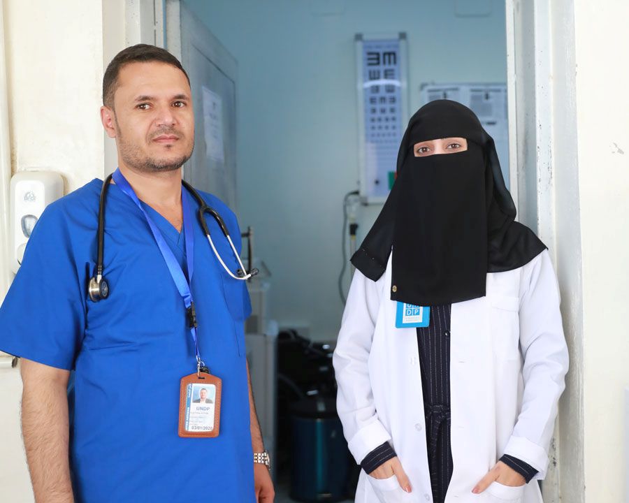 عاملان في المجال الصحي يقفان جنباً إلى جنب داخل عيادة