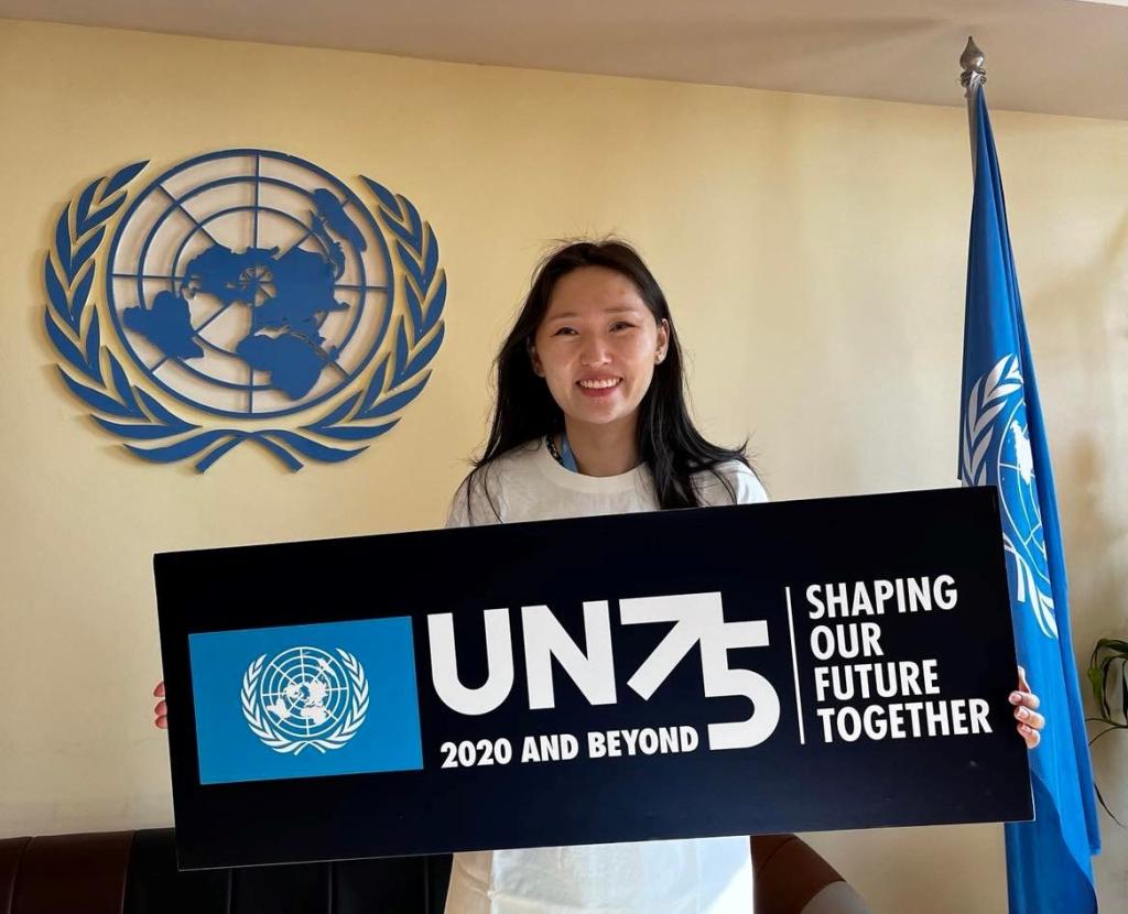 Suvd Bold, National UN Volunteer Specialist, Humanitarian Affairs officer holds a placeholder at the UN 75 celebration