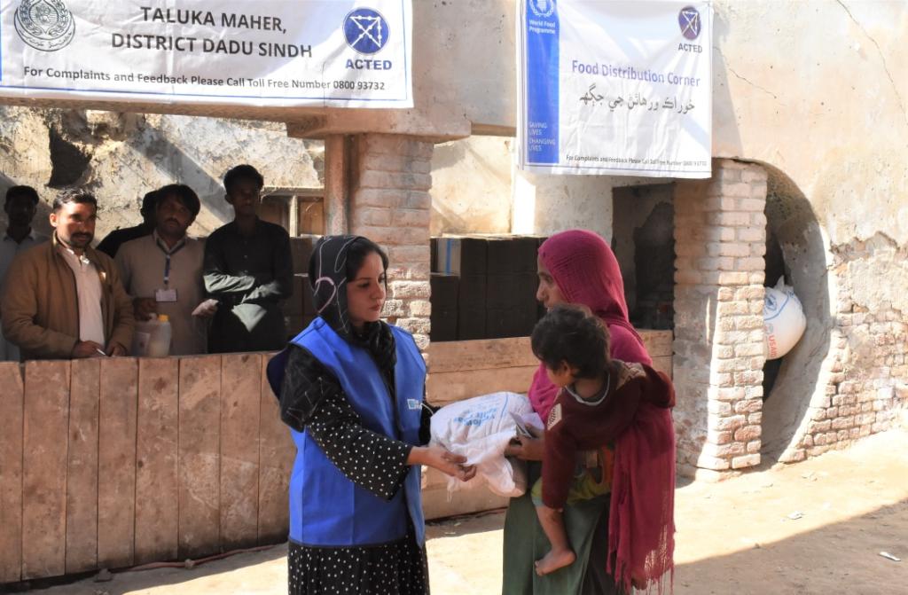 Sanam Gul (left), Community UN Volunteer with WFP Pakistan visits Dadu district to distribute food ratio to the affected people