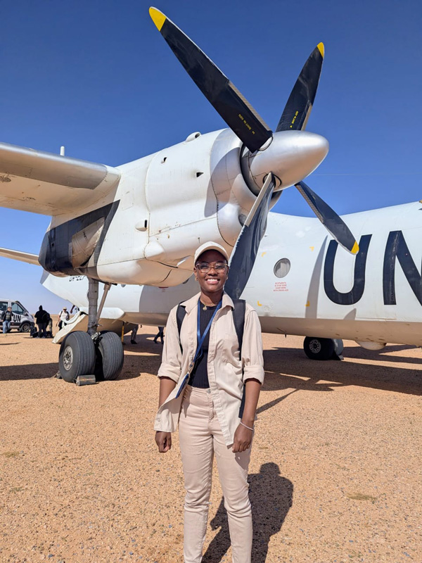 A woman standing outdoors with a UN-branded plane in the background