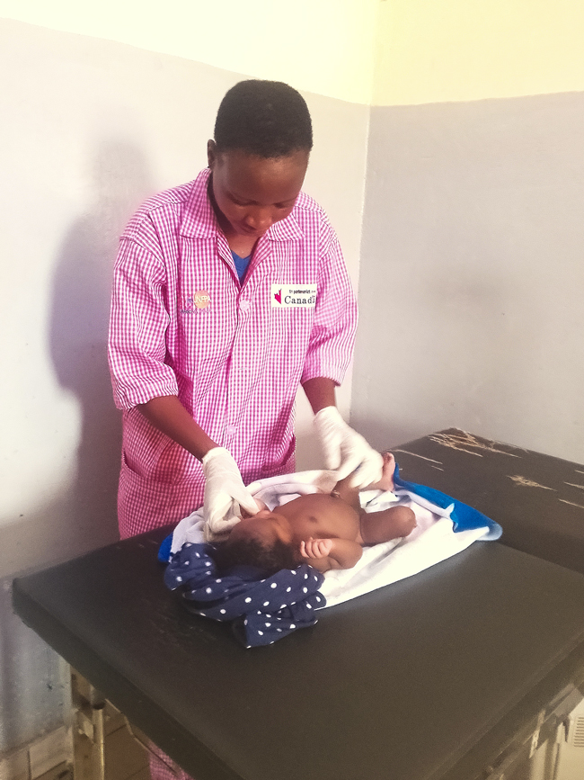 Agathe Ouoba, UN Volunteer Midwife with UNFPA, conducts an immediate neonatal clinical examination just minutes after delivery at the Diapaga Medical Centre.