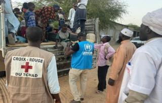Franck Ndohessengar (in blue), UN Volunteer Technical Associate and Project Management Engineer, assists Sudanese refugees with special needs as they disembark from a truck during their relocation to the Kounoungou Camp Transit Centre in May 2023.