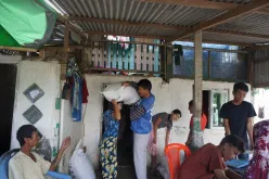 Bhone Myint Aung (center in blue) national UN Volunteer with UNDP distributes paddy bags to farmers as part of Cyclone Mocha emergency response to affected communities in Sittwe township, Myanmar.