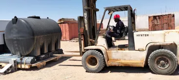 A man operating a forklift in a camp site