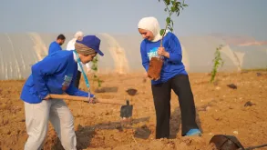 UN Volunteers Ola Al-Zubi (left) and Lina Kadri (right) planting a citrus tree in Deir 'Alla, Jordan Valley, in celebration of International Volunteer Day 2022.