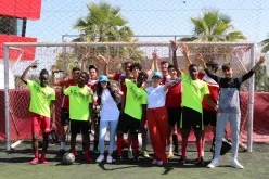 A group of young people in sportswear posing in front of a football goal.