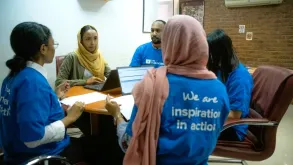 UN Volunteers Menwa Mohammed (left), Samah Ahmed (centre left) and Ziyad Ibrahim (centre), all serving with UNDP Sudan, having a discussion about inter-departmental collaboration before the war broke out in the country.