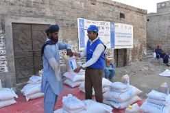Wajahat Hussain Soomro (right), Community UN Volunteer, Monitoring Assistant with WFP Pakistan distributes food ratio to the affected people in Larkana district