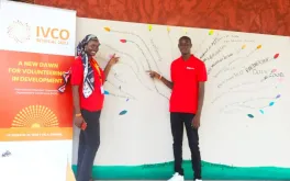 UN Volunteers Aminata Diouf and Moustapha Dia contribute to “The Mural” at the 2022 IVCO Conference in Dakar. Participants were asked to identify a word, phrase, statement or symbol that reflects volunteering. UN Volunteers point to the UNV slogan &quot;INSPIRATION IN ACTION.&quot;