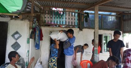 Bhone Myint Aung (center in blue) national UN Volunteer with UNDP distributes paddy bags to farmers as part of Cyclone Mocha emergency response to affected communities in Sittwe township, Myanmar.