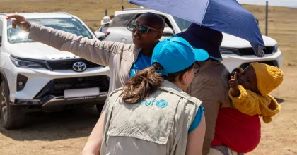 Francesca Conte (left, wearing a blue cap), Social Policy Officer at UNICEF Lesotho, shares a joyful moment with a baby in Thaba-Tseka, Lesotho.