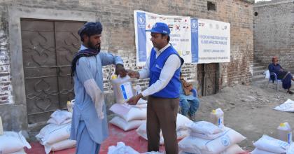 Wajahat Hussain Soomro (right), Community UN Volunteer, Monitoring Assistant with WFP Pakistan distributes food ratio to the affected people in Larkana district