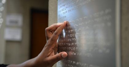 information panel in braille at an office setting being read by a hand