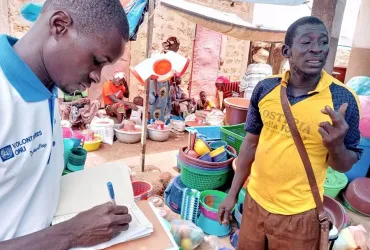 Le Volontaire Communautaire ONU Denis Simah collecte les impôts des habitants de Bagassi dans le sud du Burkina Faso.