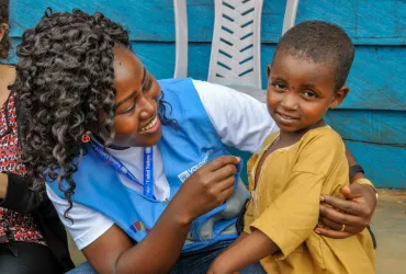 Marriane Enow Tabi, UN Volunteer Monitoring Assistant with the World Food Programme in Meiganga, Cameroon, with a child from the Lolo refugee site.