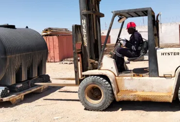A man operating a forklift in a camp site