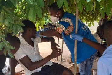 Emmanuel Chileshe Musonda (avec un gilet bleu), Volontaire des Nations Unies, adjoint à la santé et à la nutrition du HCR Zambie, aidant dans la campagne de vaccination contre la COVID-19 du ministère de la Santé lors de l’arrivée de réfugiés dans la zone d’installation de Mantapala.