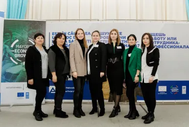 Oksana Vlasenko, UN Volunteer with UNDP Moldova, is standing in front of a backdrop with her colleagues in UNDP Moldova office.