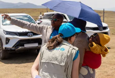 Francesca Conte (left, wearing a blue cap), Social Policy Officer at UNICEF Lesotho, shares a joyful moment with a baby in Thaba-Tseka, Lesotho.