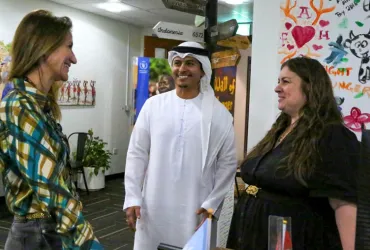 Three people engage in discussion at an office.