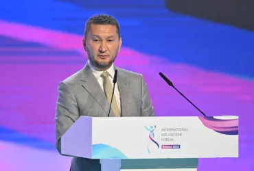 UNV Executive Coordinator Toily Kurbanov standing at a podium addressing participants in the International Volunteer Forum in Astana, Kazakhstan.