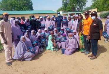 El Voluntario de las Naciones Unidas Emmanuel Egorp (de naranja) sensibilizando a estudiantes y profesores en la Escuela Gubernamental Modelo del GRA, Maiduguri, estado de Borno, durante la celebración del Día de la Higiene Menstrual el 28 de mayo de 2022.