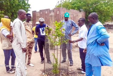 UN Community Volunteer Abdoulahat Ngom (second from right) and an accompanying delegation from the Food and Agriculture Organization engage with participants in reforestation activities carried out at Ndiob elementary school.