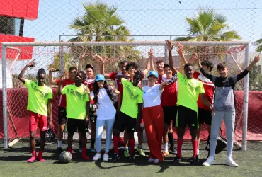 A group of young people in sportswear posing in front of a football goal.