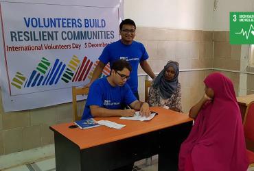 On International Volunteer Day, Jainarayan Singh (seated, India), UN Volunteer Medical Doctor with UNDP, offers refugees a health check-up at Hargeisa Group hospital, Somalia.