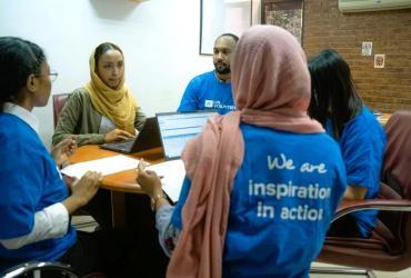 UN Volunteers Menwa Mohammed (left), Samah Ahmed (centre left) and Ziyad Ibrahim (centre), all serving with UNDP Sudan, having a discussion about inter-departmental collaboration before the war broke out in the country.