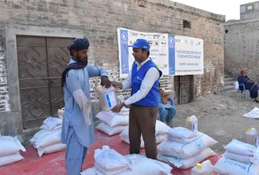 Wajahat Hussain Soomro (right), Community UN Volunteer, Monitoring Assistant with WFP Pakistan distributes food ratio to the affected people in Larkana district