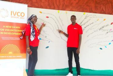 UN Volunteers Aminata Diouf and Moustapha Dia contribute to “The Mural” at the 2022 IVCO Conference in Dakar. Participants were asked to identify a word, phrase, statement or symbol that reflects volunteering. UN Volunteers point to the UNV slogan "INSPIRATION IN ACTION."