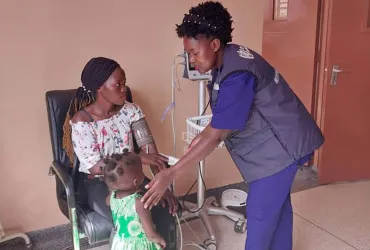 Maria Gorret Nantaayi, UN Volunteer Nurse and Case Management Officer with WHO, taking the blood pressure of a patient at the Entebbe Survivors Clinic.