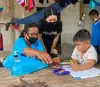 UN Volunteer Rasa Pattikasemkul interacts with a young boy in a rare face-to-face meeting during COVID-19 lockdown.
