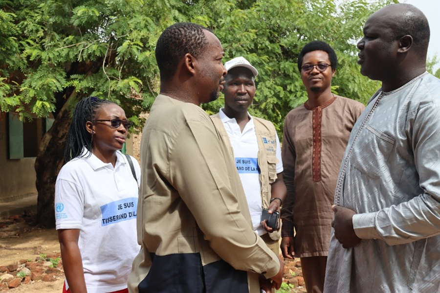 Discussion between UNESCO and UNODC personnel, the secretary general representing the prefect of the Lac Léré department and UN Volunteer Wessi Vaissoulaye (centre, in white cap) at the Young Peace Weavers training workshop in Chad in June 2022. ©UNV, 2022