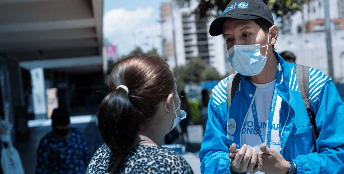 UN Volunteer with a facemask talking to a woman